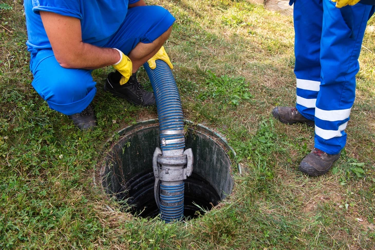 Intervention d'urgence en extérieur avec équipe de secours en combinaisons de protection orange et bleue intervenant sur citerne cylindrique métallique rouillée