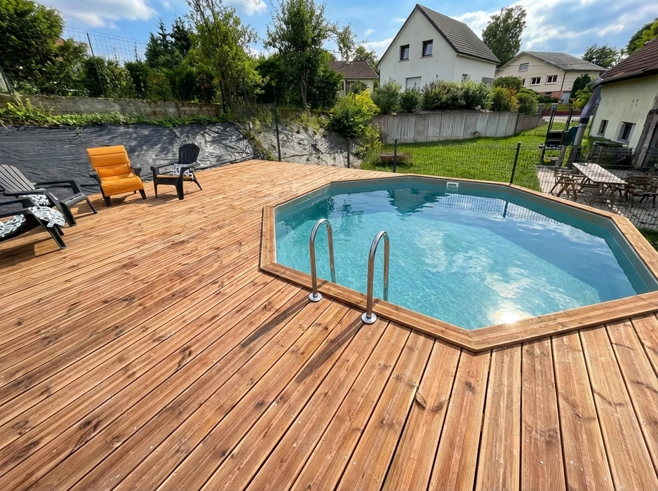 Terrasse en bois composite avec piscine hors-sol octogonale à parois bois, liner gris-bleu, échelle inox double rampe