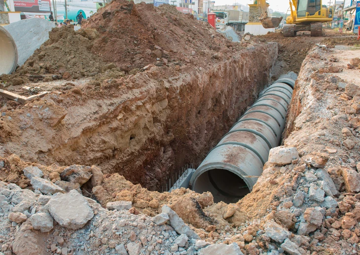 Chantier extérieur d'installation d'assainissement avec regards en béton partiellement enterrés