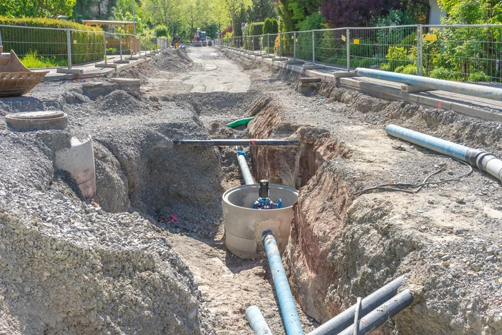 Scène extérieure urbaine montrant une bouche d'égout carrée en fonte installée dans une chaussée asphaltée