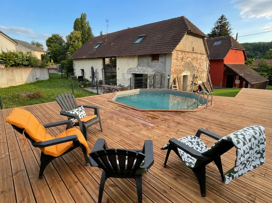 Terrasse en bois composite avec piscine hors-sol octogonale à margelles bois, entourée de chaises longues Adirondack noires avec coussins orange et motifs géométriques verts