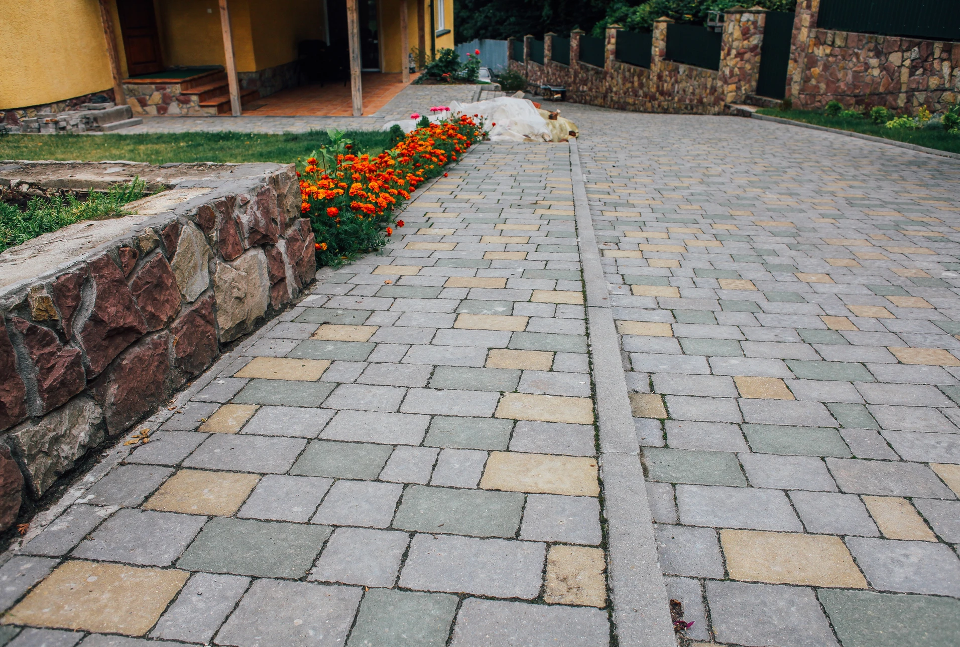 Ouvrier en tenue de travail installant un pavage ext&eacute;rieur, agenouill&eacute; sur chauss&eacute;e en pav&eacute;s de granite