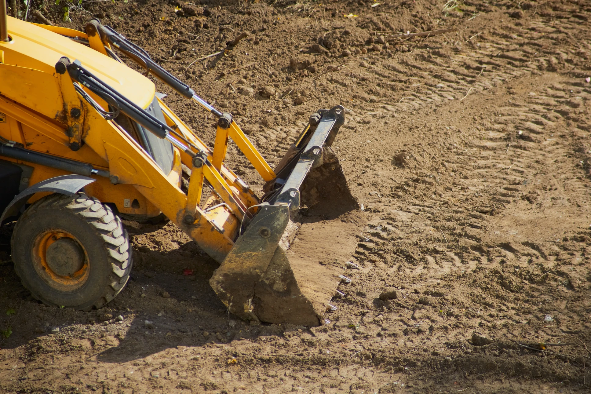 Chantier de construction extérieur avec engin de terrassement à chenilles stationné sur terrain rouge argileux