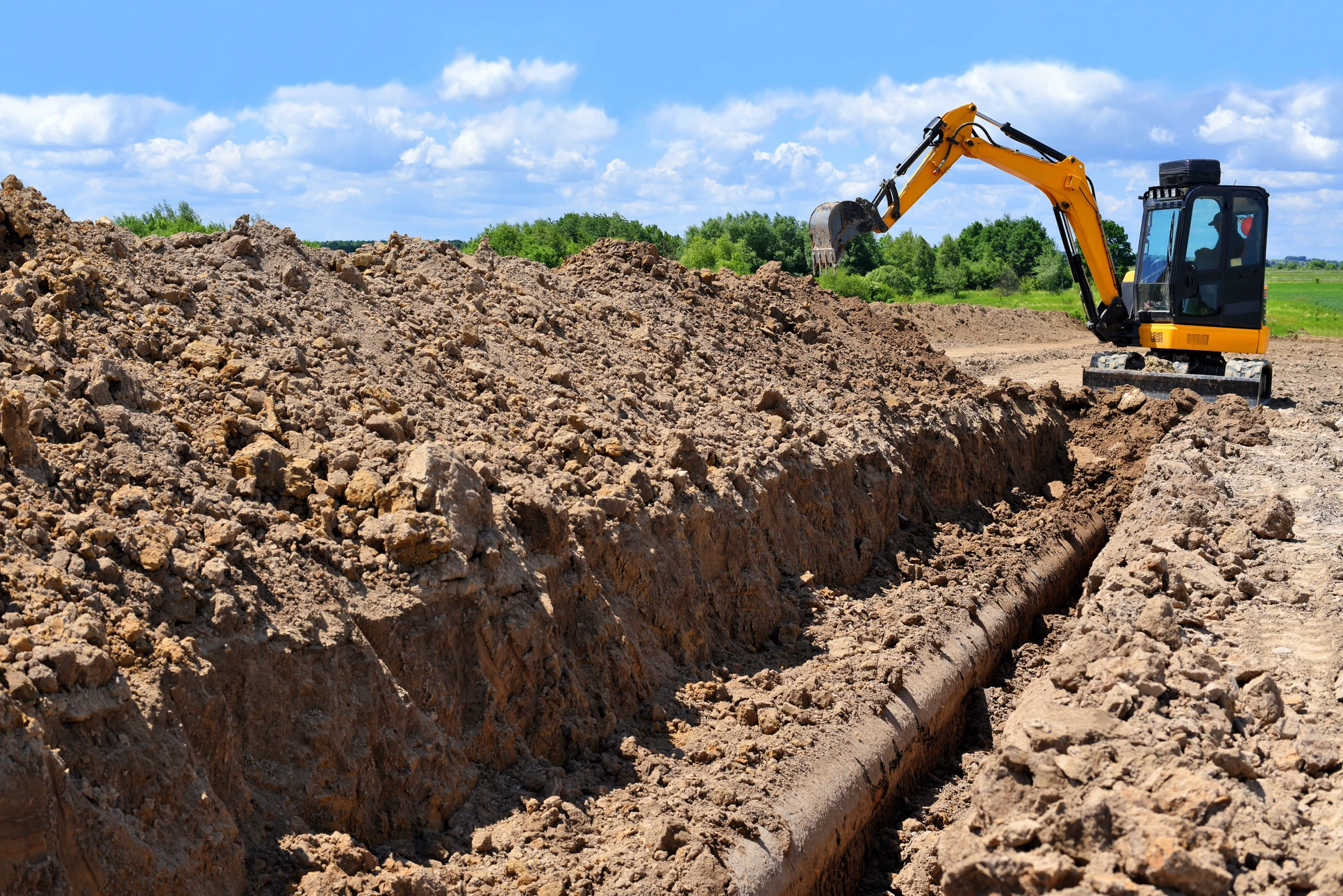 Chantier de canalisation en ext&eacute;rieur avec ouvrier en gilet haute visibilit&eacute; et casque jaune installant une vanne sur conduite d'eau